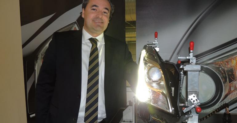 Steacutephane Veacutedie president and CEO of Automotive Lighting North America stands beside Cadillac XTS headlamp